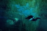 The diver watches the stalactite and stalagmite formations of the cave of Karavomilos. They are quite big and the water is very clear.